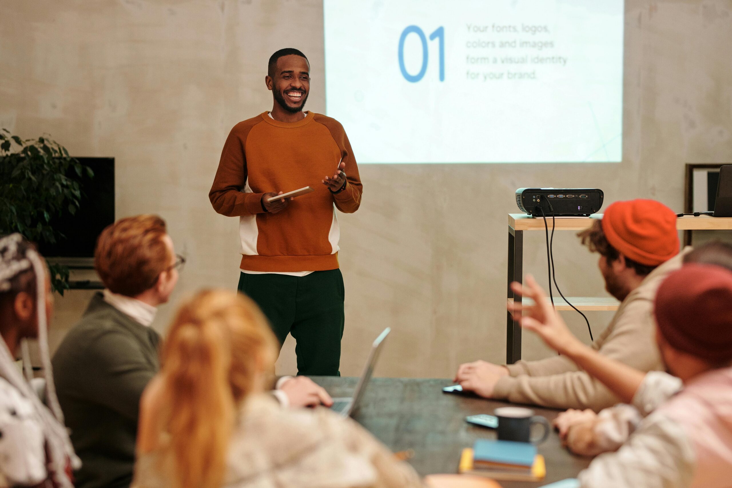 SERVICES A man delivers a presentation in a modern office to a diverse group of colleagues.