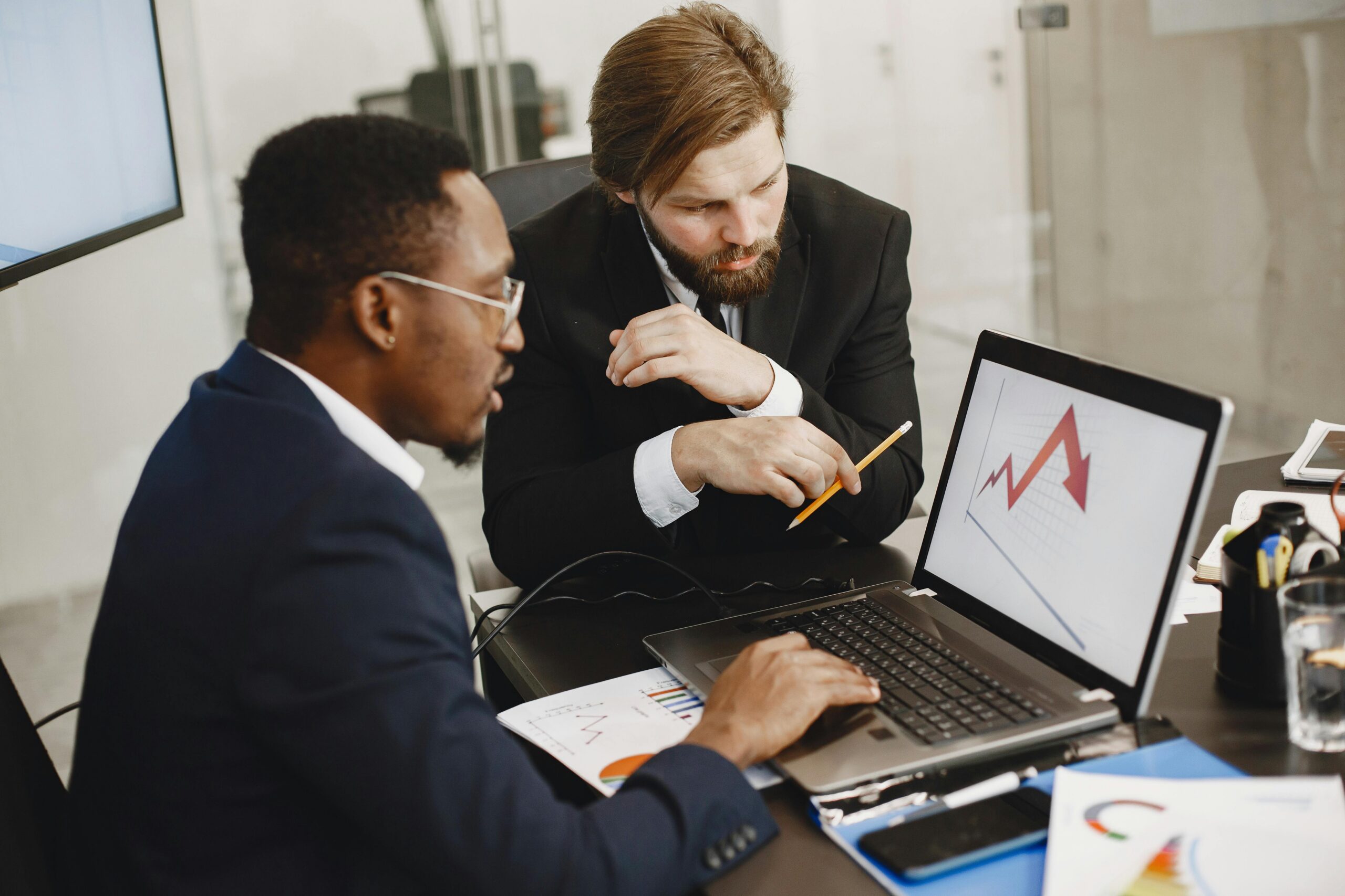 SERVICES Two business professionals discuss marketing data on a laptop in a modern office.